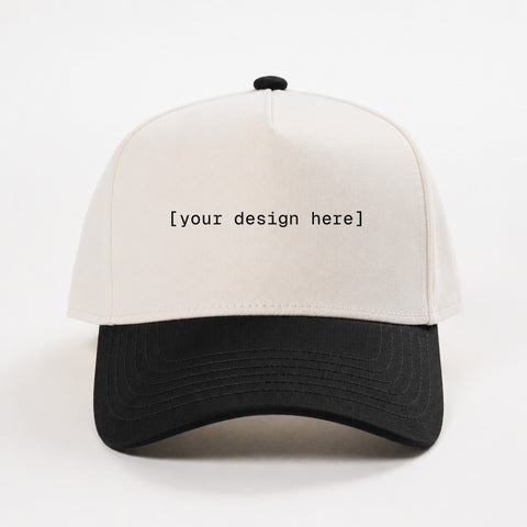 White and black cap with 'your design here' text on a white background