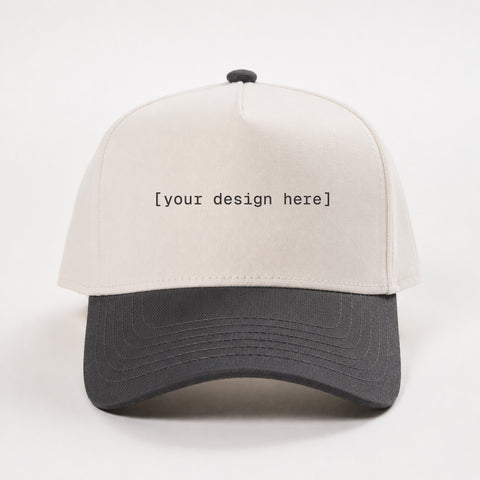 White and black cap with 'your design here' text on a white background