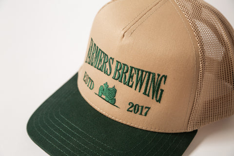 Beige and green cap with embroidery 'Farmers Brewing' text on a white background