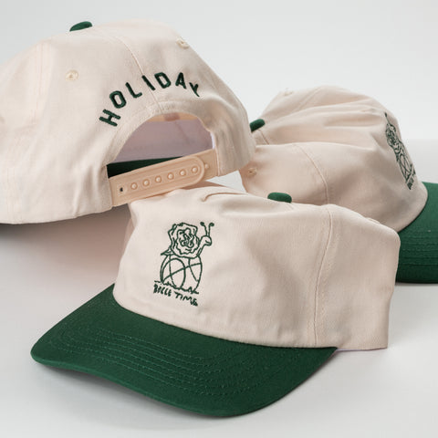 Three beige and green caps with custom embroidery different designs on a white background