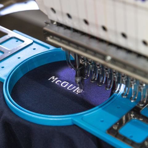 Embroidery machine in action with text on a blue hoop.