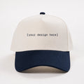 White and navy cap with 'your design here' text on a white background