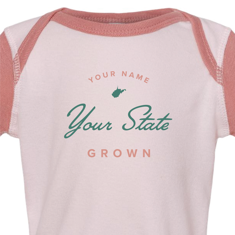 Detail shot of custom baby onesie reading "your name, your state, grown" and a US state silhouette